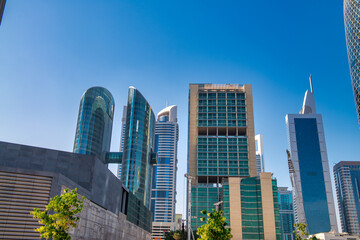 Fototapeta premium Downtown Dubai's gleaming skyscrapers under intense desert sunlight with modern towers reflecting blue skies and golden rays