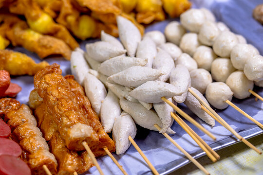Meatballs on a stick, Assorted street food skewers including sausages, fish balls, and crab sticks displayed at a market stall. Grilled meatballs, Fried meatballs, ready to eat and visually appealing