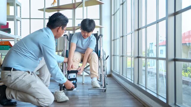Father adjusting orthopedic ankle brace for young boy in wheelchair, highlighting family support and rehabilitation care