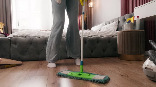 Caucasian woman happy washing floor with mop dancing listening music in headphones listen song in earphones in bedroom home cleaning house work joy fun fooling funny housekeeping routine enjoying move