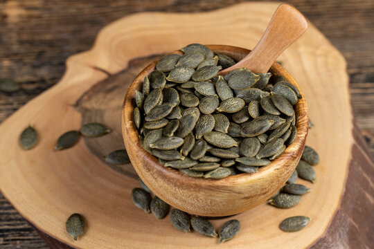 peeled large dried pumpkin seeds are lying on a wooden walnut board and in wooden dishes, a large number of healthy large pumpkin seeds without shells are ready for cooking and eating