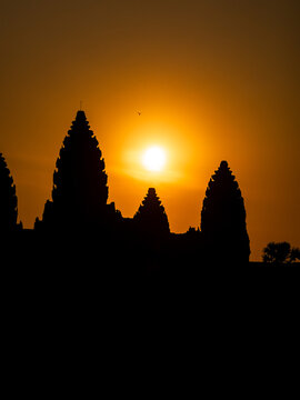 View of the ancient temple silhouettes against the fiery sunset, creating a stark contrast between the darkness and the golden glow, Siem Reap, Cambodia.