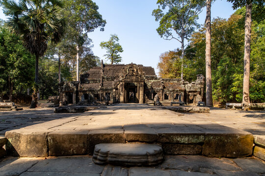 View of ancient stone blocks in the foreground lead the eye to the weathered Banteay Kdei Temple under a clear blue sky, Siem Reap, Siem Reap Province, Cambodia.