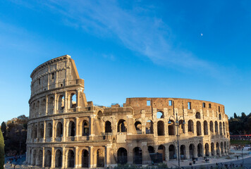 Obraz premium Famous Coliseum in Rome. Colosseum, or Coliseum. Sunset at huge Roman amphitheatre, Rome, Italy, Europe. Famous touristic place in the world and Europe. Beautiful blue sky background.