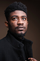 Obraz premium Young Black man with textured hair and beard looking upwards thoughtfully