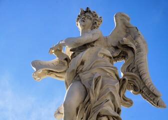Obraz premium Close up of the beautiful white marble statue of an angel with a scroll reading INRI on Ponte Sant'Angelo, the historic angel bridge in Rome, Italy
