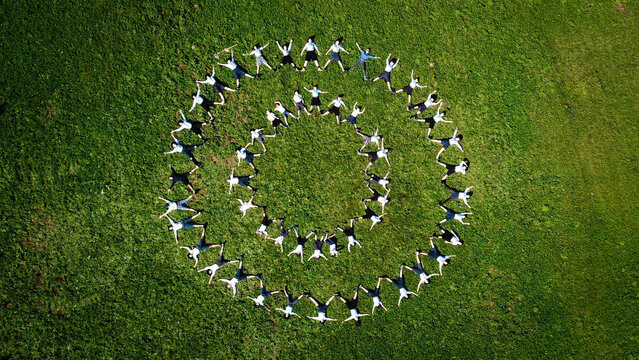 Aerial view of people forming a spiral in a vibrant green field, a captivating display of teamwork and unity, Bogeve, Auvergne-Rhone-Alpes, France.