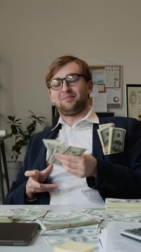 Vertical portrait of materialistic self-satisfied gen Z manager dressed formally throwing money on office desk smiling for camera