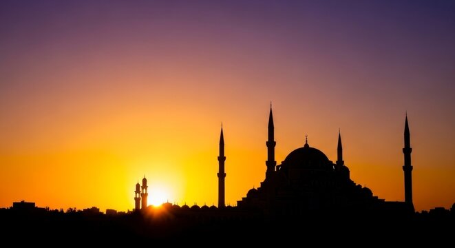 Silhouette of a mosque at sunset with vibrant orange and purple hues