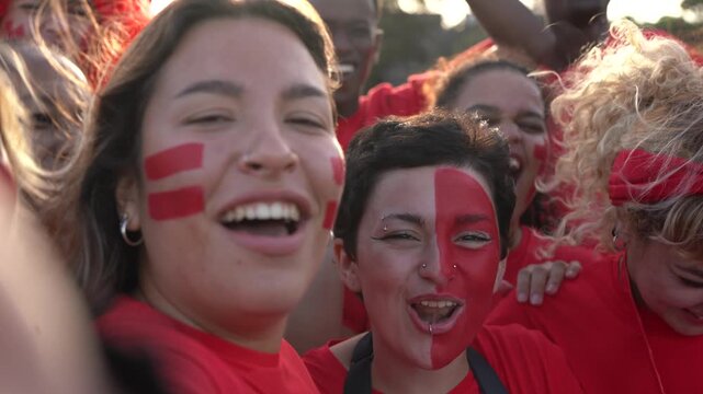 Multiracial football supporter fans streaming live video at stadium - People with red t-shirts having excited fun on sport world championship