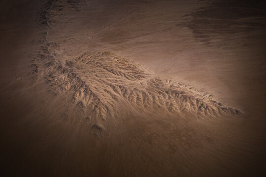 Aerial view of intricate dendritic erosion patterns in the desert sand with soft shadows and textured dunes Walvis Bay, Erongo Region, Namibia.