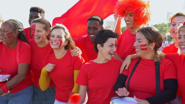 Multi generational sport fans people having fun screaming outside of stadium - Group of red football supporters celebrating goal outdoor 