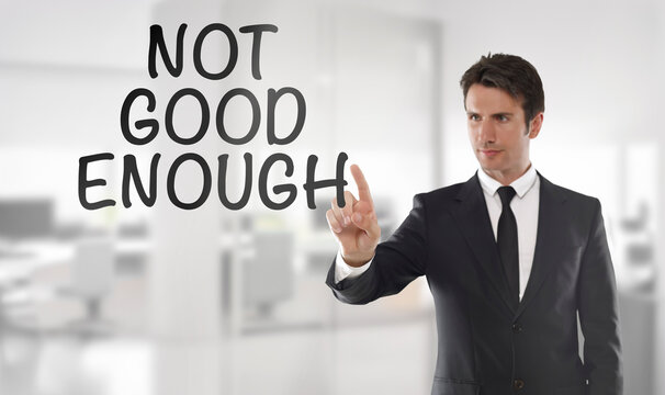 Businessman touching "Not good enough" text on transparent wipe board in an office