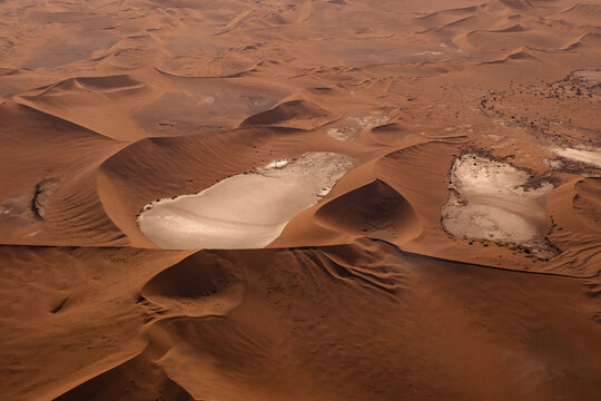 Aerial view of red sand dunes and white salt pans in the Namib Desert near Walvis Bay, Erongo Region, Namibia.