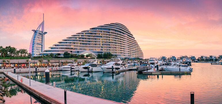 10 January 2026, Dubai, UAE: Modern city marina with luxury yachts, Burj Al Arab and Jumeirah Beach Hotel reflecting evening light