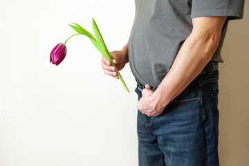 Erectile dysfunction concept. Man holding a flower bending downwards.