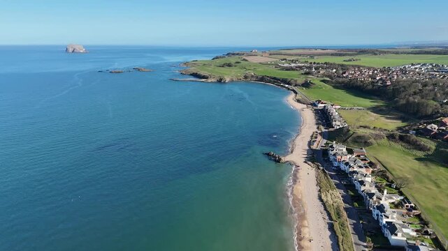 Scotland, East Lothian, North Berwick. An expansive aerial view showcases the vibrant greens of the Glen Golf Club meeting the deep blues of the Firth of Forth, with the historic Bass Rock.