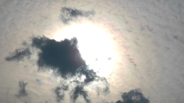 Moving natural clouds texture Altocumulus Duplicatus in sky with sun, colorful pearly glow around sunlight and bird in flight. Topics: cloud iridescence, irisation, optical phenomenon, meteorology