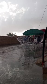 Cinematic rain falling on a quiet street in Quetta, Pakistan, moody weather landscape.