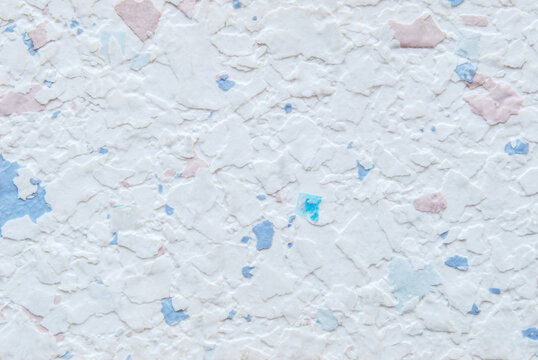 White pastel multicolor decorative flakes wall texture or pattern as background