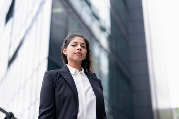 Fototapeta premium Young woman stands confidently outside a modern office building during the day