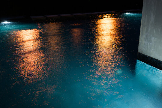 Blue water in swimming pool with rain drops in night