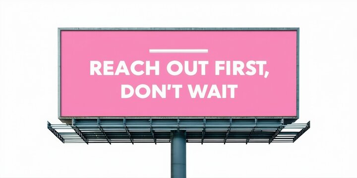 Billboard displays motivational message. Pink background, bold text reads Reach out first, dont wait. Simple design, clear communication.