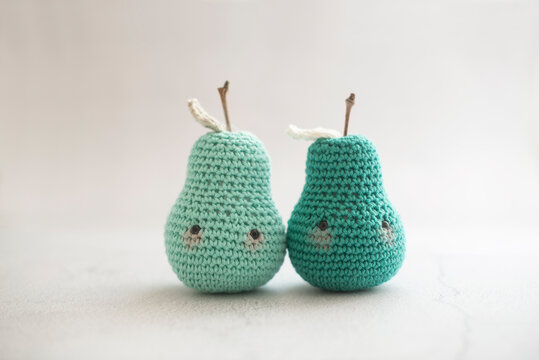 Close-up of two homemade anthropomorphic crochet pear toys (Amigurumi) next to each other on a table