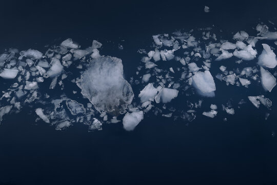 View of various ice chunks and small icebergs floating in the deep dark blue waters of the Arctic Ocean Greenland.