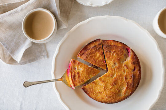 Close-up overhead view of a sugar free low carb cherry and strawberry cake made with coconut and almond flour on a table with two cups of white coffee