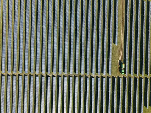 Aerial view of endless rows of solar panels stretching across the landscape, a stark contrast to the surrounding green fields, Felixstowe, United Kingdom.