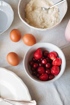 Close-up of overhead view of assorted Baking ingredients for making a cake including eggs, strawberries, cherries and gluten free almond and coconut flour