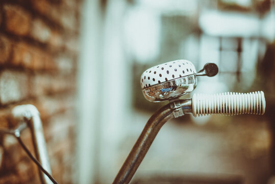 Close-up of a polka dot bicycle bell on the handlebars of a bicycle leaning against a brick wall