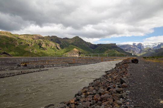 Hiker crosses a walking bridge over a river in Thorsmork Iceland