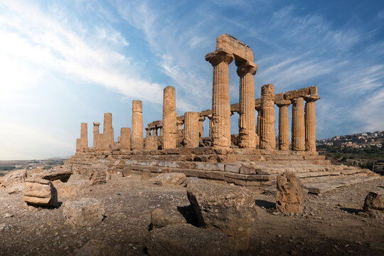 View of ancient Greek Doric columns of the Valley of the Temples under a bright blue sky with soft clouds Agrigento, Sicily, Italy.