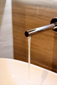 Close-up of a modern chrome tap with running water in a stylish bathroom