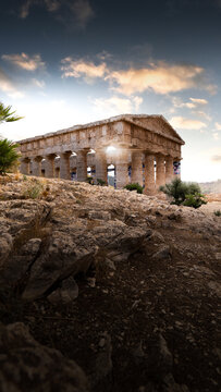 View of the ancient Doric Temple of Segesta standing on a rocky hill under a sunset sky with warm light in Segesta, Sicilia, Italy.