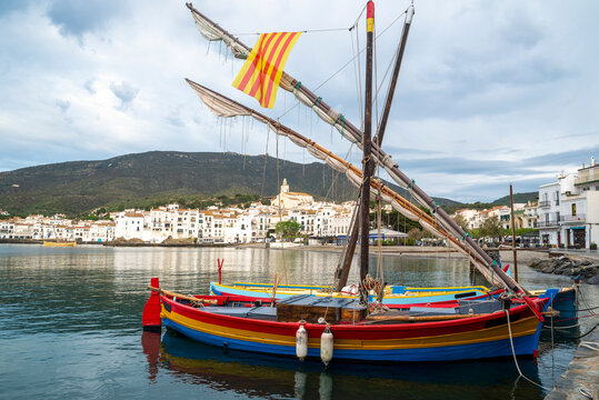 Traditional Colourful fishing boats moored in the harbour with coastal townscape of Cadaques, Girona, Catalonia, Spain