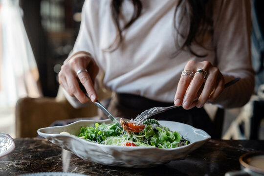 Close-up of Woman sitting at a table eating a fresh tuna salad with tomatoes and grated cheese