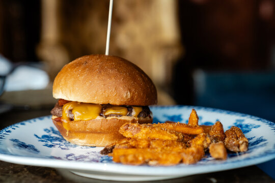 Close-up side view of a Gourmet Beef Cheeseburger with Crispy Sweet Potato Fries on a plate