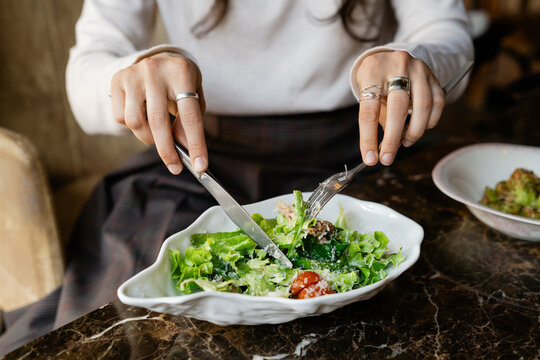 Close-up of Woman sitting at a table eating a fresh tuna salad with tomatoes and grated cheese