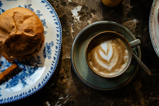 Overhead view of a cappuccino with a Gourmet Beef Cheeseburger with Crispy Sweet Potato Fries