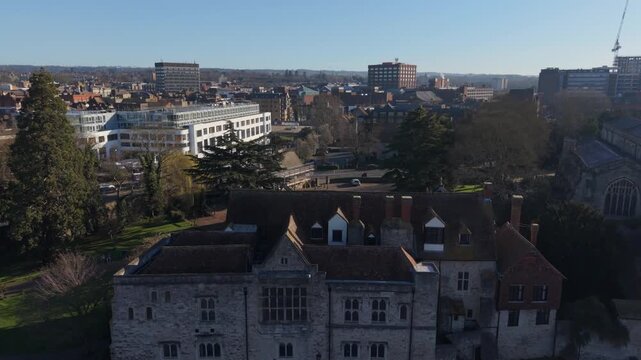 Maidstone town and historic Archbishop's Palace early in the morning. Aerial rising view of business town skyline on a sunny Sunday. Public park and historic landmark by the river.