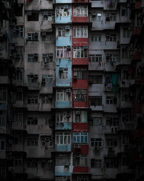 View of the dense residential facade of the Monster Building featuring colorful vertical sections and many air conditioning units in Hong Kong.