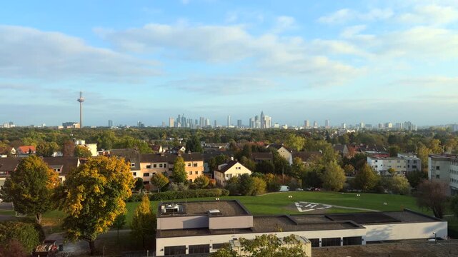 Distant view of Frankfurt am Main skyline with the Europaturm, surrounded by suburban residential houses and autumnal trees from countryside