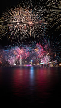 View of colorful fireworks exploding over the illuminated skyline and Victoria Harbour at night Hong Kong.