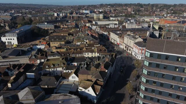 Aerial view of Maidstone town center above High street flying towards Medway river. Tall office building and old town center with shops on a sunny morning. Business town in Kent, UK.