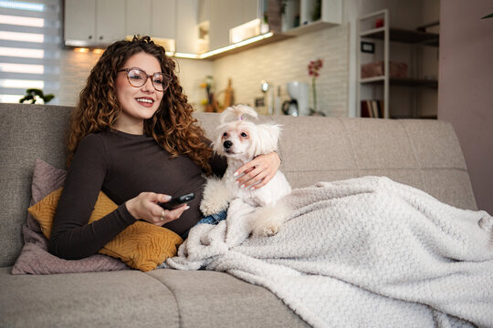 Woman relaxing at home with dog watching television