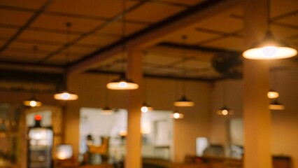 Fototapeta premium Warm blurred interior of a cafe with hanging pendant lights