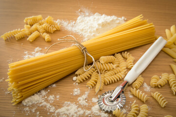 Differenti tipi di pasta cruda su un tavolo da cucina © errem